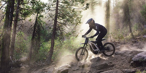 a person riding a bike on a dirt trail in the woods