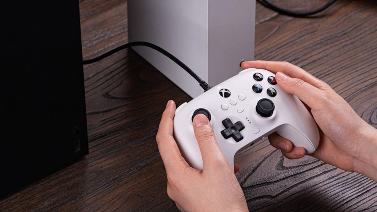 Image showing a person holding 8BitDo's Ultimate wired controller in white.